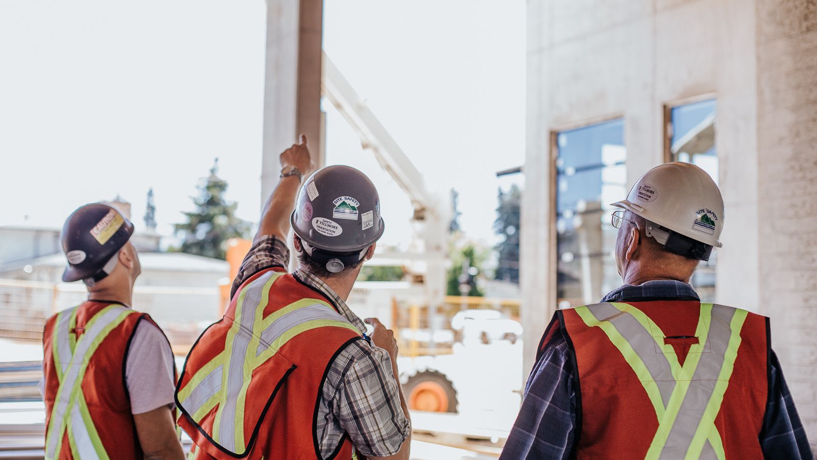 Three Kelco Drywall workers under a site under construction sign, pursuing careers with Kelco.